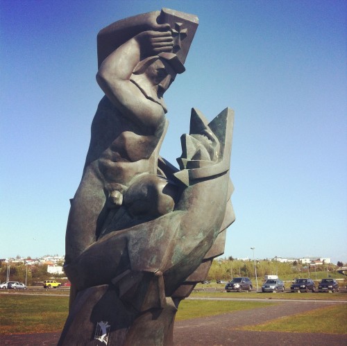 A statue at the University of Iceland of a man smacking a devil/seal with a bible
