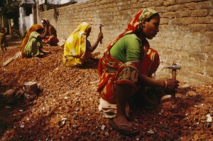 Poor women break bricks with hammers near a construction site.