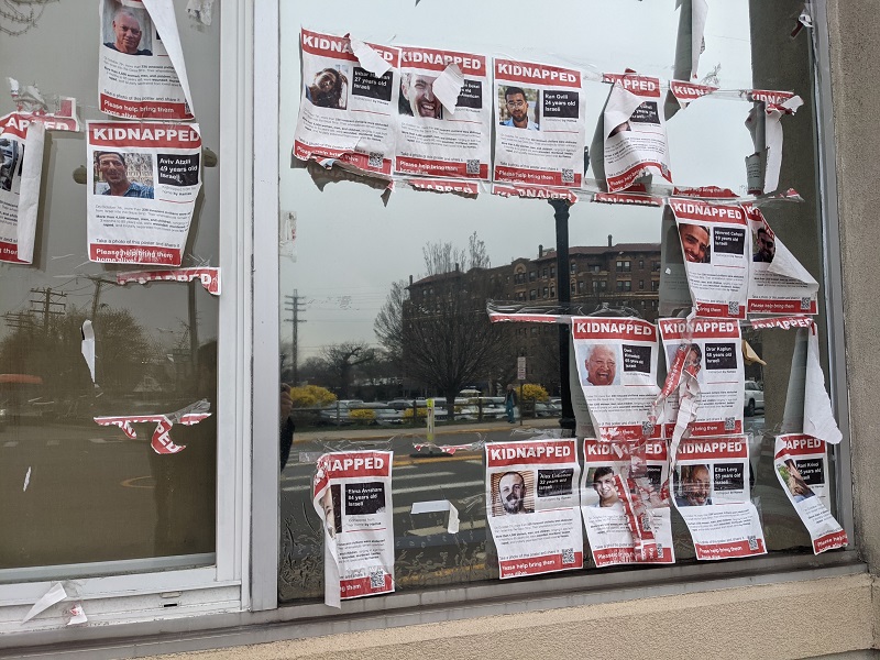 A window with tattered posters listing the names of Israeli hostages taken by Hamas