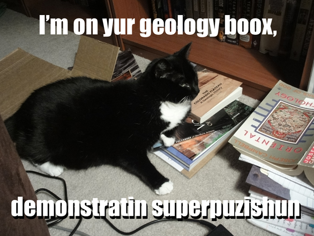 Image shows Misha lying on a pile of geology books. Caption says, "I'm on yur geology goox, demonstratin superpuzishun."