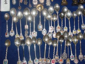 A collection of souvenir silver spoons with enamel coats of arms on their handles. Photo by Lourdes Cardenal via Wikimedia Commons.