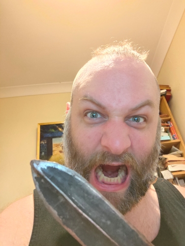 The image shows me, being manly. You can tell how manly I am by the beard, the aggressive facial expression, and the edged weapon. You could argue that the mohawk/ponytail is also a pretty masculine look, but in this picture it just looks like I have a little tuft of hair on top of my head. 
