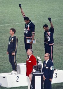 American sprinters Tommie Smith and John Carlos, along with Australian Peter Norman, during the award ceremony of the 200 m race at the Mexican Olympic games. During the awards ceremony, Smith (center) and Carlos protested against racial discrimination: they went barefoot on the podium and listened to their anthem bowing their heads and raising a fist with a black glove. Mexico City, Mexico, 1968. 